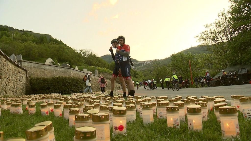 Herdenkingskaarsen met bergen en fietsers op de achtergrond